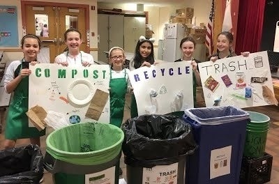 Pupils standing behind their compost and recycling bins, holding up posters