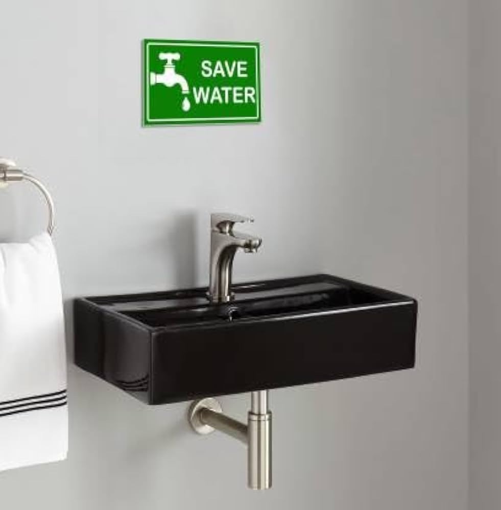 Un autocollant vert « Save water » au mur, au-dessus d'un petit lavabo